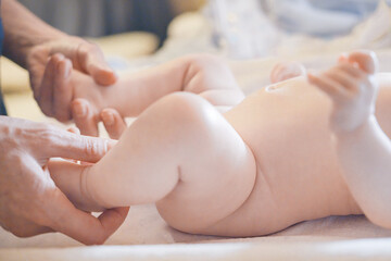 Adorable baby newborn enjoying massage from mother. Mom massaging little baby's foot, making strengthening gymnastic with her newborn child.