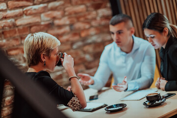 Happy businesspeople smiling cheerfully during a meeting in a coffee shop. Group of successful business professionals working as a team in a multicultural workplace.