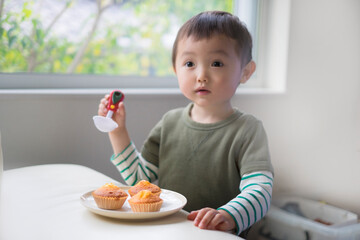 マドレーヌをおたまで食べようとする2歳児