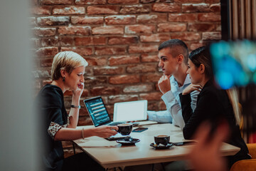 Happy businesspeople smiling cheerfully during a meeting in a coffee shop. Group of successful business professionals working as a team in a multicultural workplace.