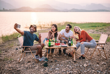 Group of diversity friends enjoy camping and make a selfie with beautiful sunset view at the lake -...