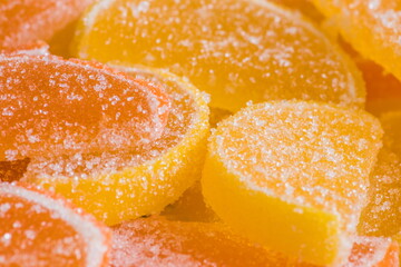 Decorative Background of yellow and orange marmalade candy in shape of citrus fruits wedges. Jelly sweet candies. Food Texture. Beautiful square Wallpaper or Web banner.