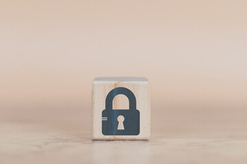 cyber security wood cube concept, man's hand laying down a wood cube with a padlock icon, to convey...