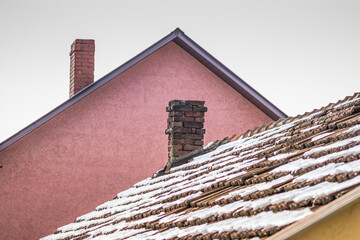 Roof of a private house in the snow. Tiled roof in the snow. Winter time. The roof is covered in snow. Part of roof clear from snow.