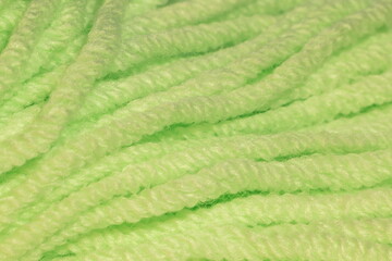 The texture of the rope light green in a skein. Abstract background.A skein of light green thick thread very close