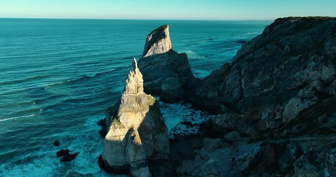 Aerial view pf the most western point of the European continent - Cabo da Roca, Portugal. Drone flies over the Atlantic ocean coast, rocky formations and the beach called Praia da Ursa.