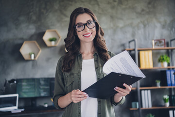 Photo of confident smiling lady secretary wear eyeglasses reading contract indoors workplace...