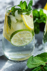 Cold lemonade with mint, lemon and lime in a glass. Preparation of lemonade