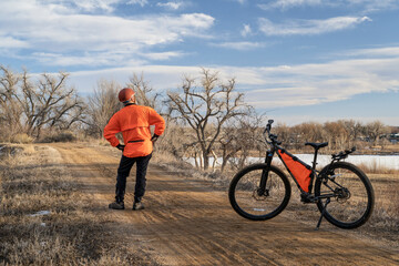 male cyclist with a mountain bike on a dirt trail, winter biking in Loveland, Colorado