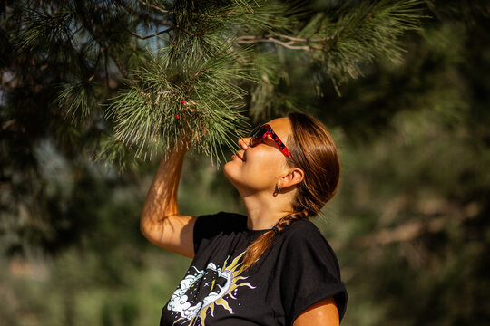 A beautiful woman in a pine forest enjoys the smells of pine trees, smells phytoncides