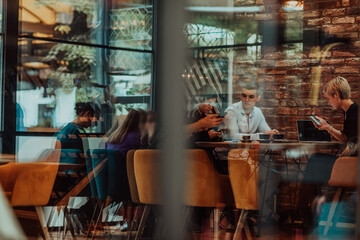 Photo through the glass of a group of business people sitting in a cafe and discussing business plans and ideas for new online commercial services