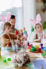 Happy father with little kids decorating easter eggs.