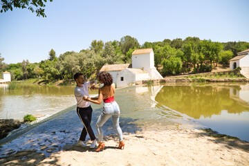 beautiful woman and handsome man latinos dancing bachata are dancing by the river in the forest....