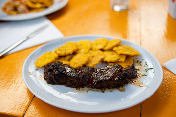 tostones with beef fillet served on white plate. Fried green plantain. Dominican food. Stepped potato.