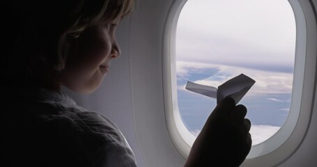 A little boy plays with a paper airplane, dreaming of becoming a pilot. From childhood, the child set himself the goal of becoming a professional pilot. Purposeful boy plays with a paper plane.