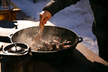 open-air kitchen, frying homemade sausages in sauce