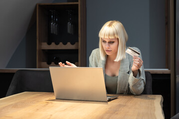 Young shocked frustrated woman holding bank credit card annoyed that she has reached her account...