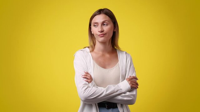 4k video of one woman who crosses her arms and responds negatively to something over yellow background.