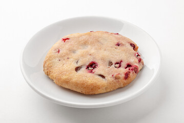 One freshly baked cranberry cookie on a white plate on the table. Homemade cakes for breakfast.
