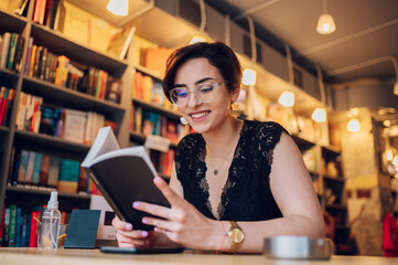Woman reading a book while relaxing in the cafe or a bookstore