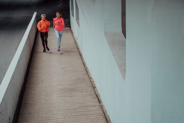 Two women in sports clothes running in a modern urban environment. The concept of a sporty and healthy lifestyle