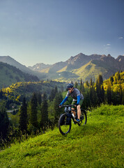 Man ride mountain bike at the green hill in the mountain of Kazakhstan