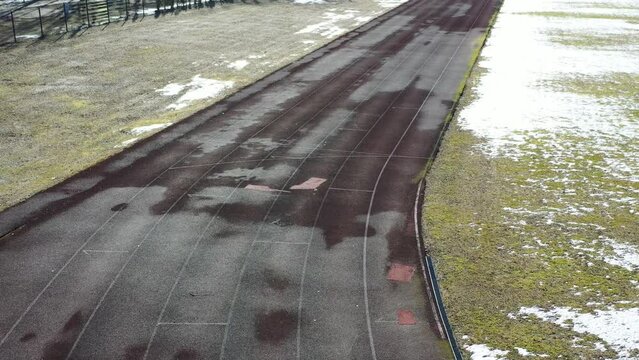 Empty snowy old stadium running track in winter, aerial view