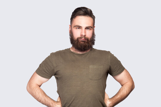 Bearded man looking cross-eyed with stupid facial expression, fooling around, keeps hands on hips.