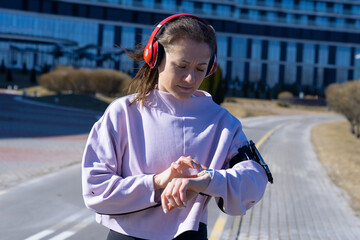 Fototapeta na wymiar Portrait of a sporty woman who listens to music and watches her activity on the clock