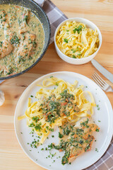 Pasta with spinach, cheese sauce and chicken breast on a plate on kitchen table