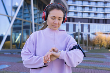 Fototapeta premium An athletic young woman adjusts her watch before running outside. Smart watches. A lover of running