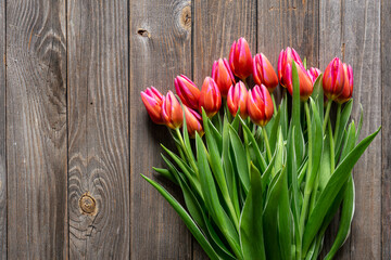 Bouquet of fresh pink tulips on a wooden background, top view, concept of mother's day, women's day, spring background with a bouquet of flowers, rustic style.