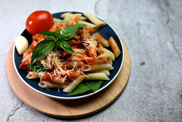 pasta in tomato sauce with basil leaf on a plate on a wooden tray
