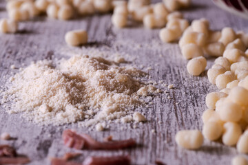 Grated Parmesan cheese and gnocchi in the background