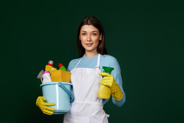 woman in cleaner apron holding bucket of detergents