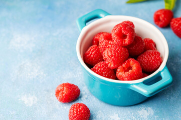 Closeup raspberry fruits in blue bowl, blue background