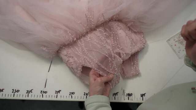 A seamstress sews sequins to a holiday dress