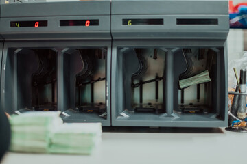 Bank employees using money counting machine while sorting and counting paper banknotes inside bank...