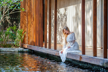 Woman relaxing at a luxury spa, barefoot on a wooden bridge