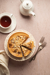 Caramel cheesecake sliced and served with cup of tea, top view