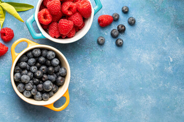 Fresh berries. Blueberry and raspberry in ceramic bowls. Colourful fruit, food background, top view.