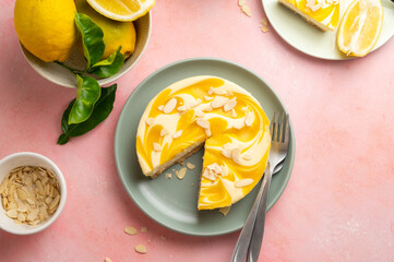 Lemon cheesecake tart or pie, with fresh lemons, pink background