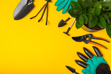 Gardening tools, pruner, gardening gloves, shovel and rake on a bright yellow background. Garden...
