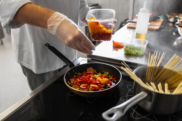 cooking food, profession and people concept - close up of male chef with frying pan stewing vegetables at restaurant kitchen