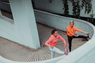 Two women warming up together and preparing for a morning run in an urban environment. Selective focus 