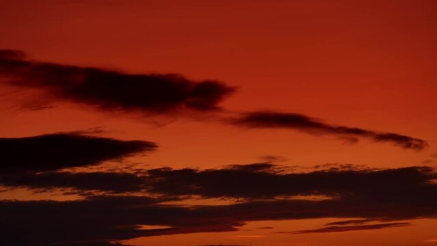 4k sunset time lapse video. Detail view of an orange dramatic sky with cumulus and cirus clouds during a spring sunset.