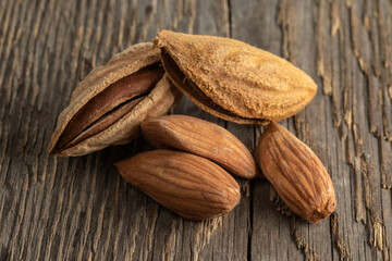 Inshell almonds on a background of rough wood texture. Selective focus.