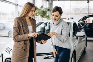 Woman in car showroom talking to salesperson