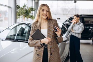 Woman choosing a car with dealership in a car showroom