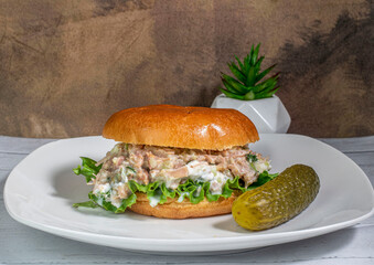 chicken salad on a brioche roll with a pickle